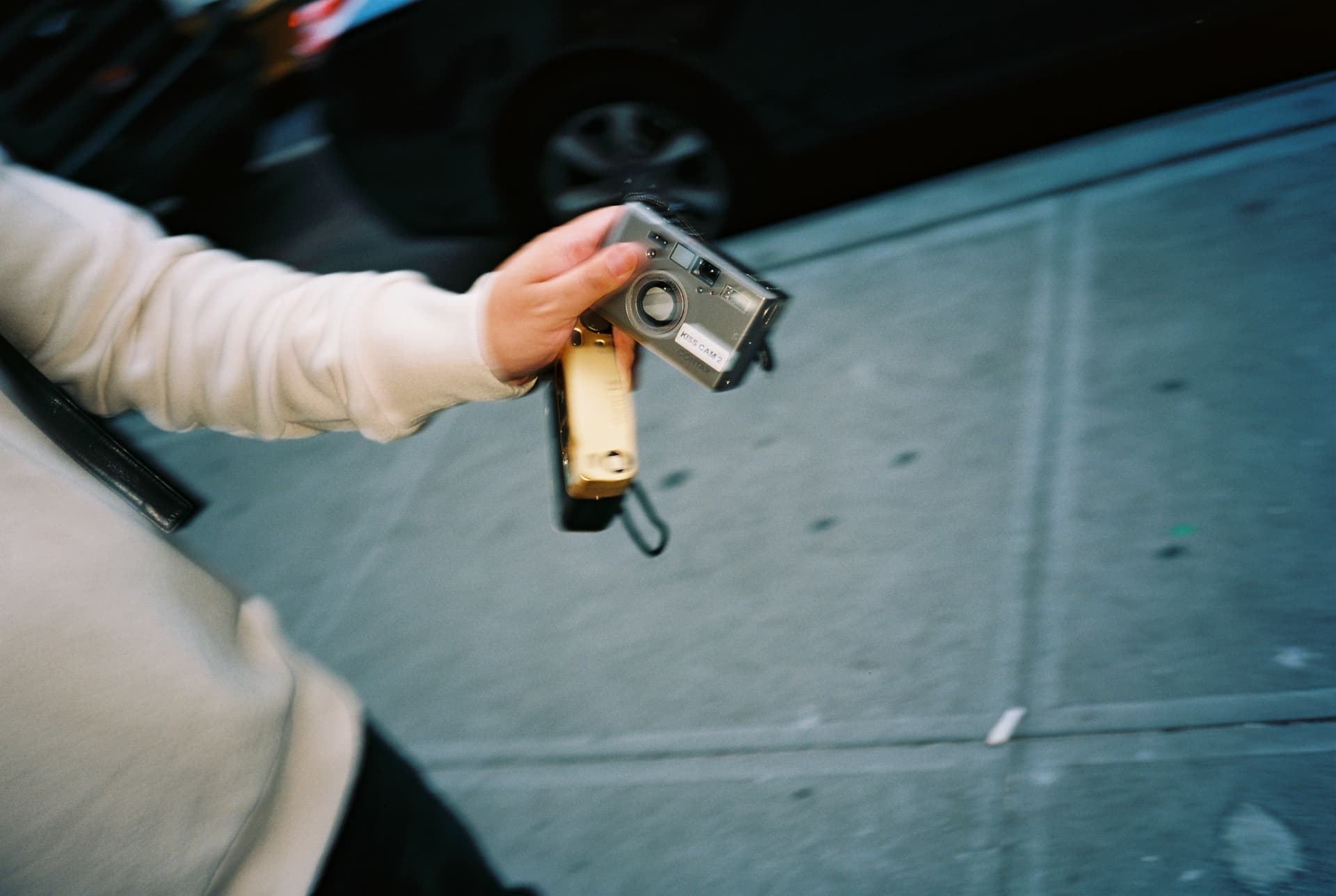 Motion-blurred hand holding a silver point-and-shoot film camera